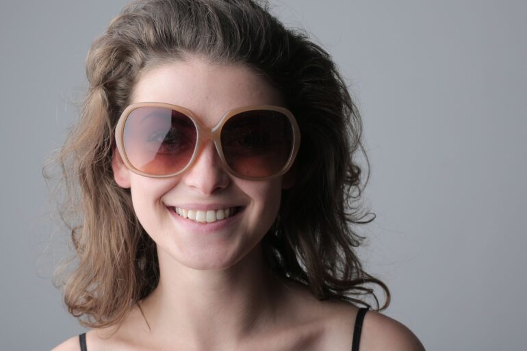Femme souriante portant de grandes lunettes de soleil rondes