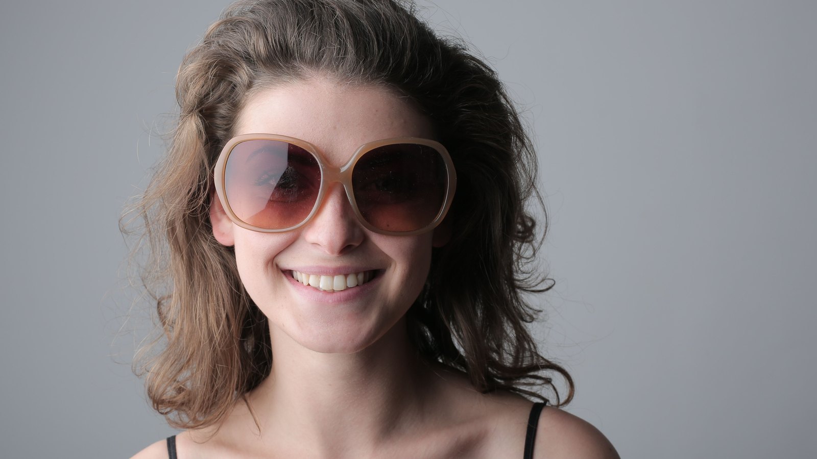 Femme souriante portant de grandes lunettes de soleil rondes