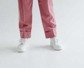 Baskets blanches portées avec un pantalon rose sur fond clair
