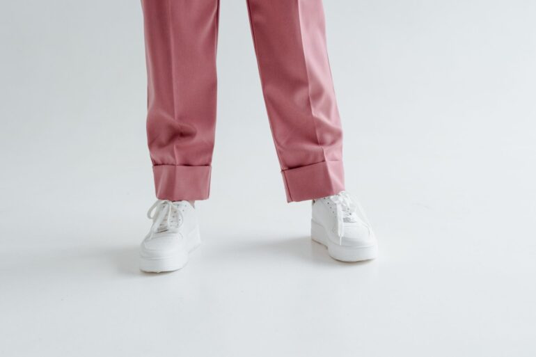 Baskets blanches portées avec un pantalon rose sur fond clair