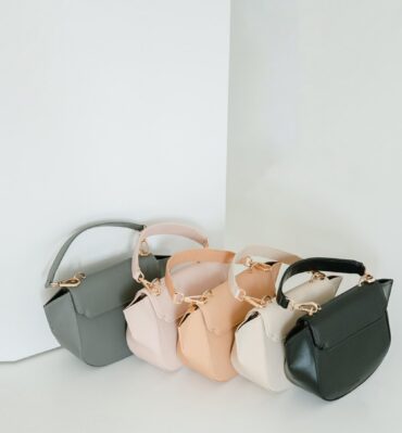 Trois mini sacs alignés, gris, beige et noir, sur fond clair