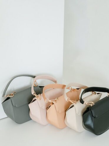 Trois mini sacs alignés, gris, beige et noir, sur fond clair