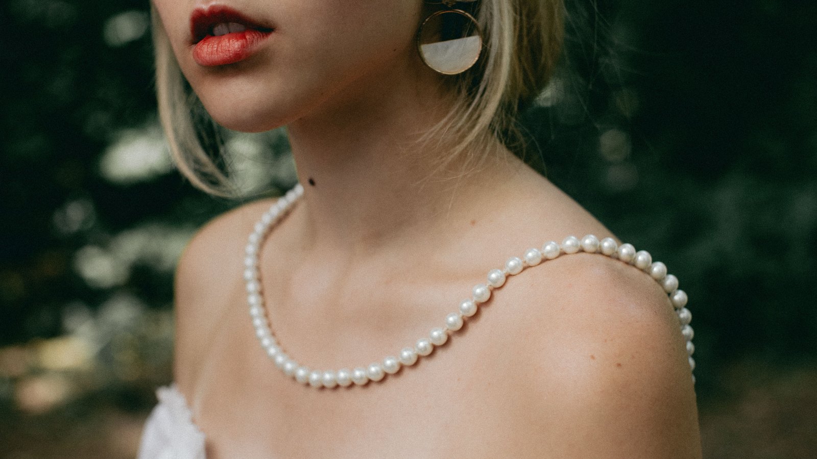 Collier de perles blanches porté sur une épaule dénudée
