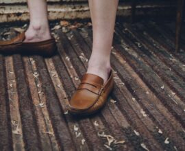 Mocassins bruns portés pieds nus sur une grille métallique