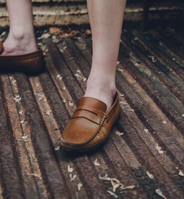 Mocassins bruns portés pieds nus sur une grille métallique