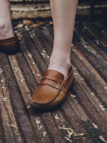 Mocassins bruns portés pieds nus sur une grille métallique