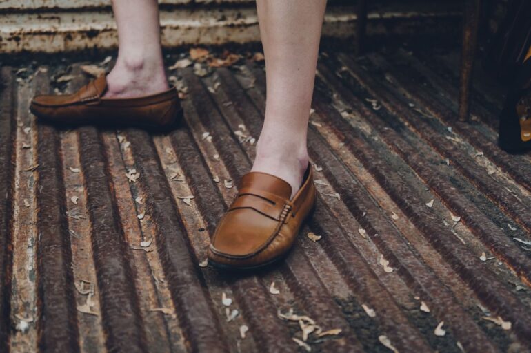 Mocassins bruns portés pieds nus sur une grille métallique