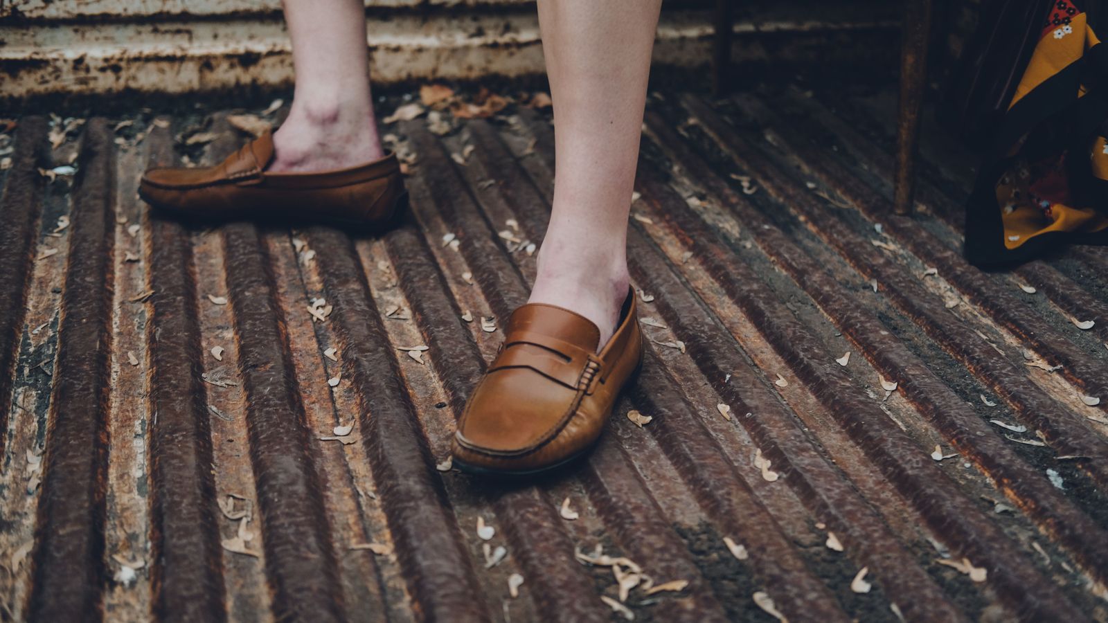 Mocassins bruns portés pieds nus sur une grille métallique