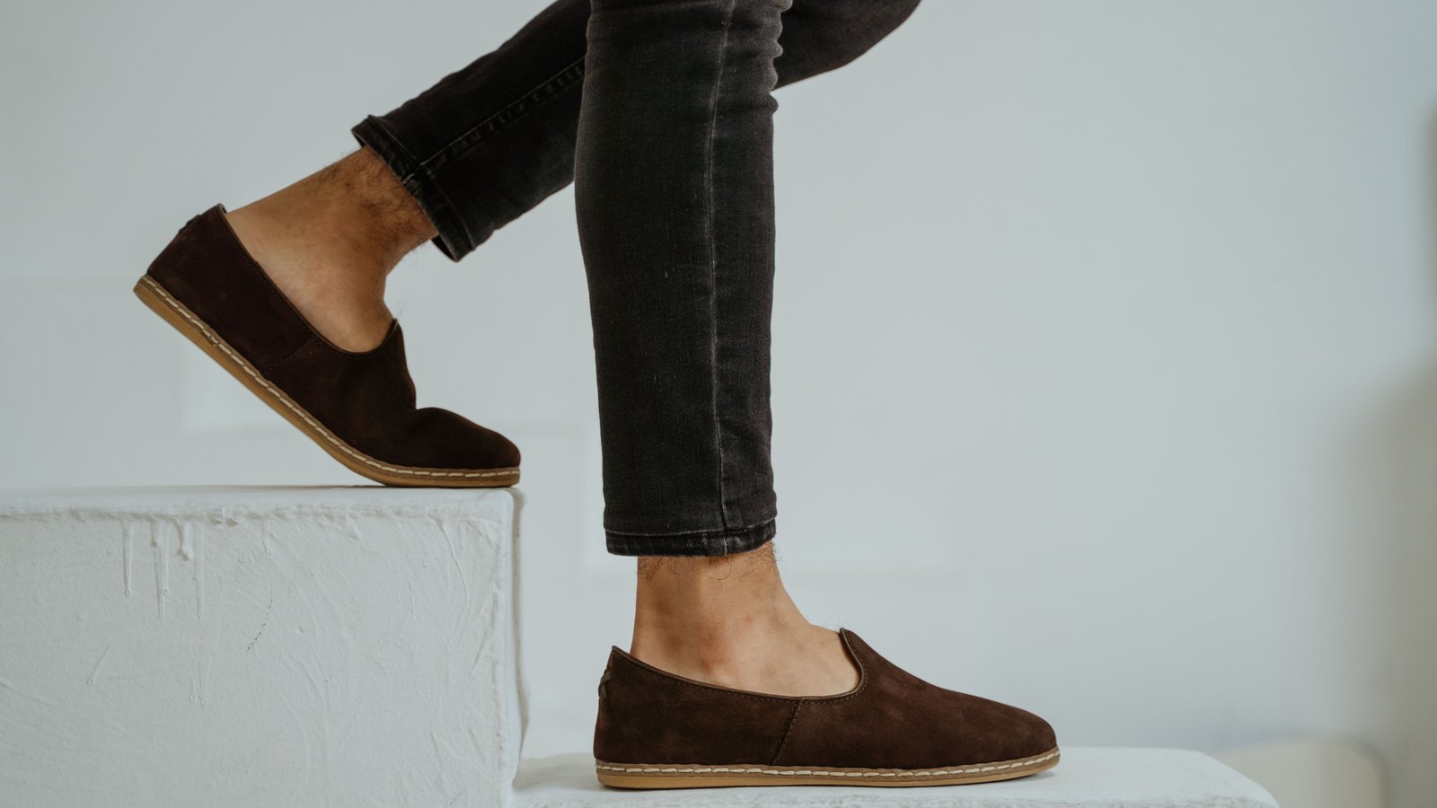 Mocassins en daim foncé portés avec un pantalon noir