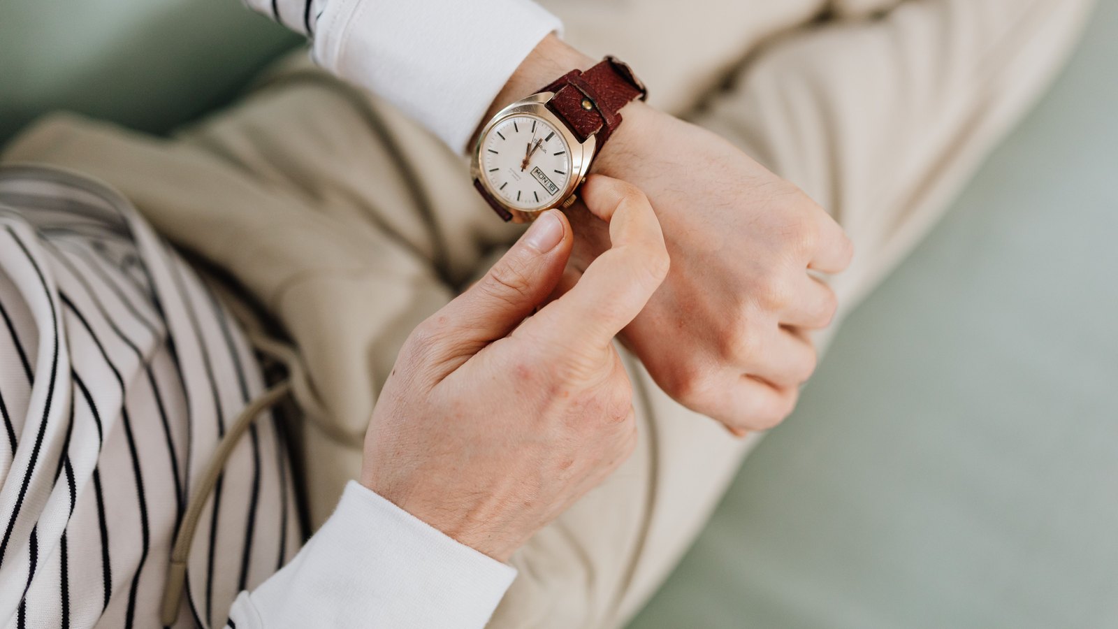 Montre à bracelet de cuir brun portée sous une manche de chemise