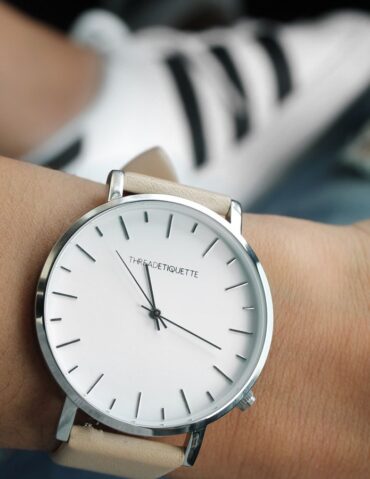 Montre à cadran blanc et bracelet clair portée au poignet