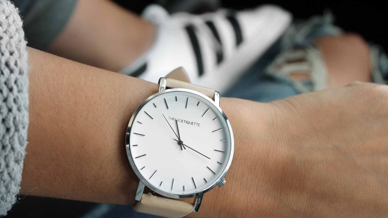 Montre à cadran blanc et bracelet clair portée au poignet