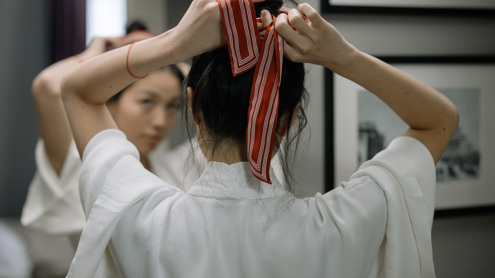 Femme nouant un foulard dans ses cheveux devant un miroir
