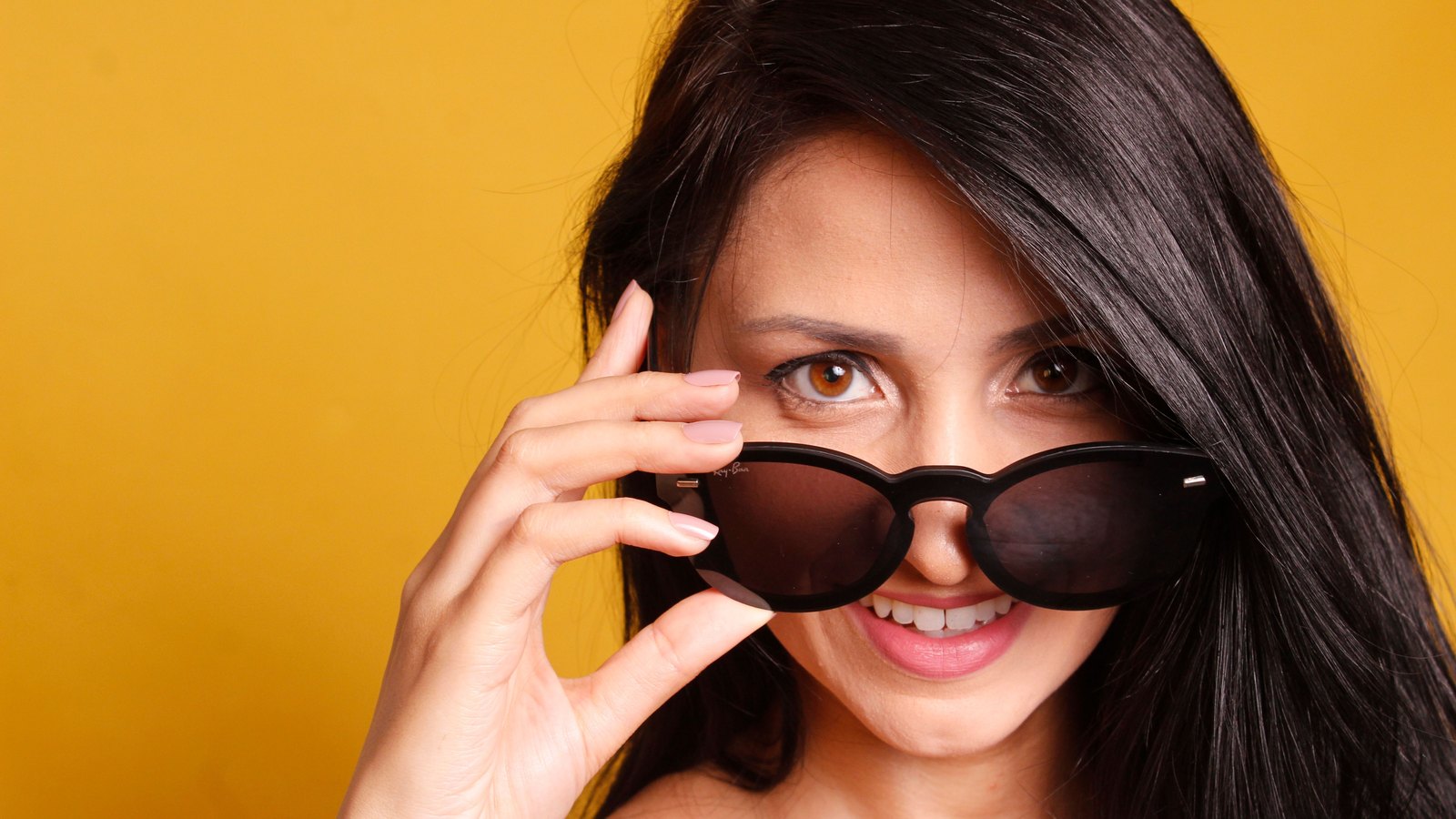 Femme abaissant des lunettes de soleil papillon sur fond jaune